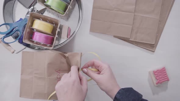 Slow motion. Making favors bags out of brown bags with stamps and ribbons for kids birthday party.