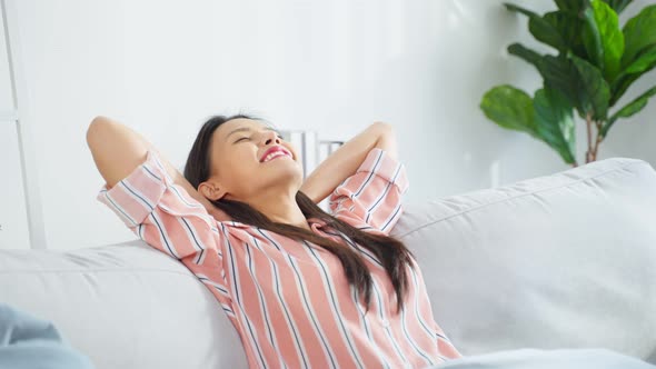 Asian beautiful girl lying down on comfort sofa in living room at home.