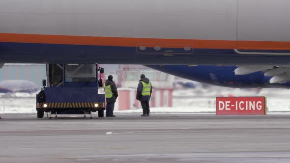 Workers preparing to de-ice a jet plane