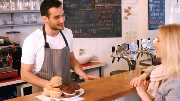 Waiter giving coffee to female customer at counter