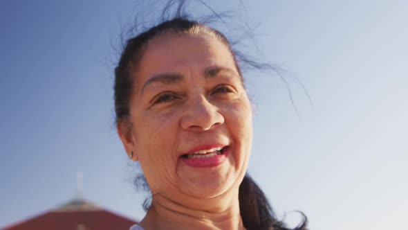 Mixed race woman looking at camera and smiling on the beach and blue sky background