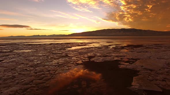 Flying over ice chunks and frozen lake during colorful sunset