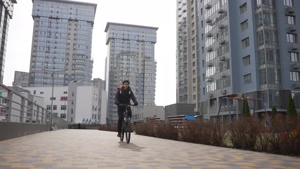 Delivery Guy Riding Bike Among Highrise Buildings