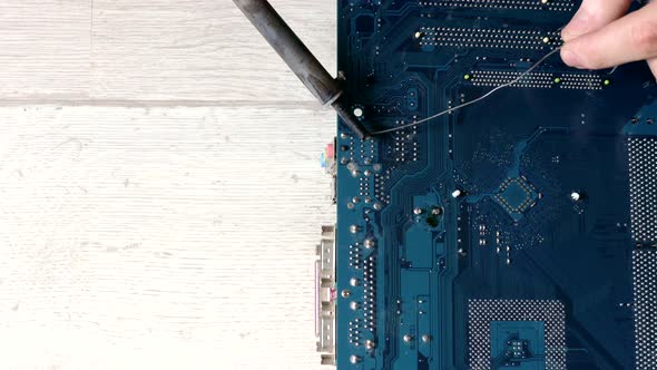 Soldering motherboard. Engineer solder a chipset under a magnifying glass