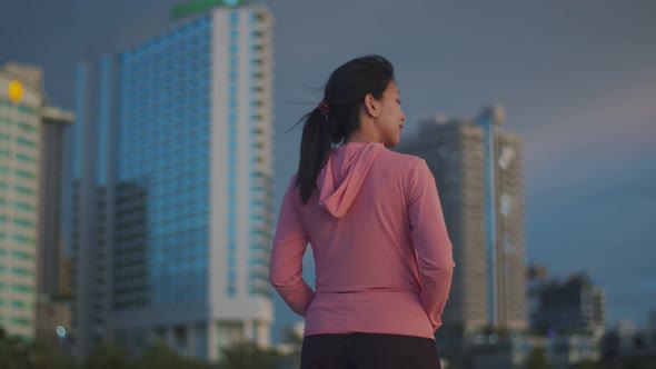 Girl in sports clothes taking a break from exercising admiring the view sunset.