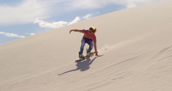 Man sand boarding on the slope in desert 