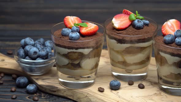 Classic Tiramisu Dessert with Blueberries and Strawberries in a Glass on Wooden Background