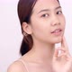 Slow motion of Asian girl with natural make up looking to camera and patting her face gently. - VideoHive Item for Sale