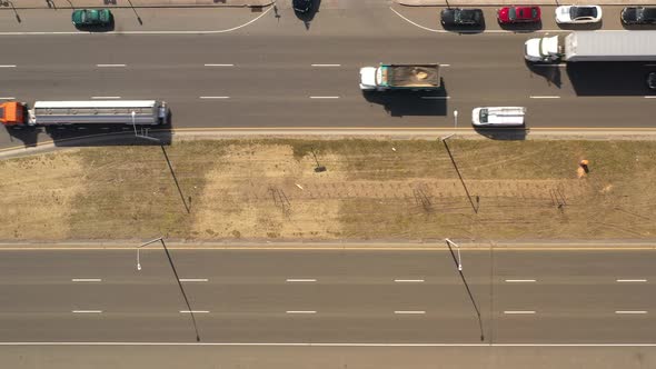 A top down view directly over a highway median on a sunny day. With traffic on either side of the me