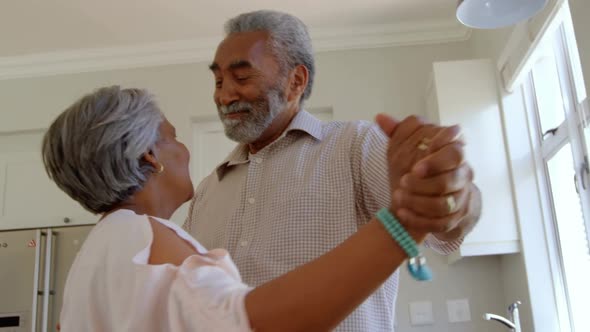 Side view of senior black couple dancing together in kitchen at comfortable home 4k