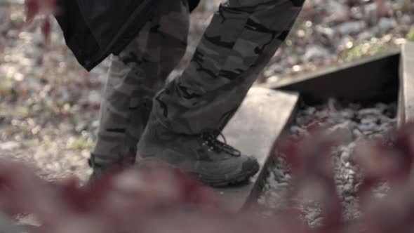 Slow motion. Low to ground shot of hiker in boots and camouflage pants walking up wooden steps outdo