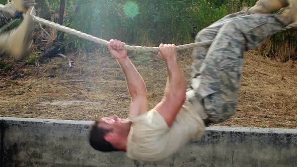 Military soldier climbing rope during obstacle course