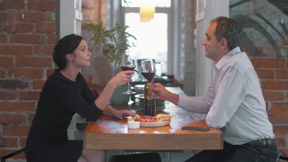 Couple at Romantic Dinner, They Clink Glasses of Wine