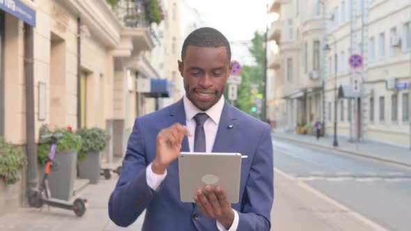 African Businessman Working on Tablet While Walking on Street