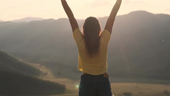 A Young Woman Comes To the Edge of a Cliff and Raises Her Hands Up in Front of the High Rocky