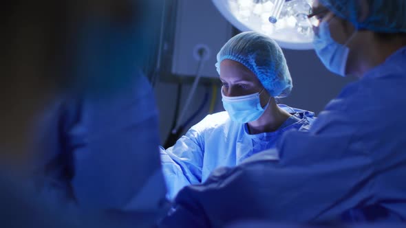 Diverse surgeons wearing face masks and protective clothing in operating theatre