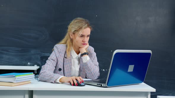 Tired Female Teacher Working on Laptop at School