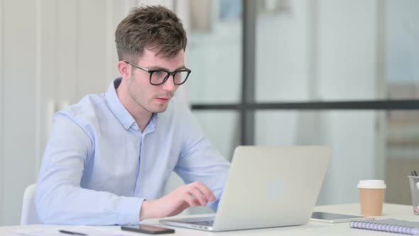 Young Man with Laptop Having Neck Pain