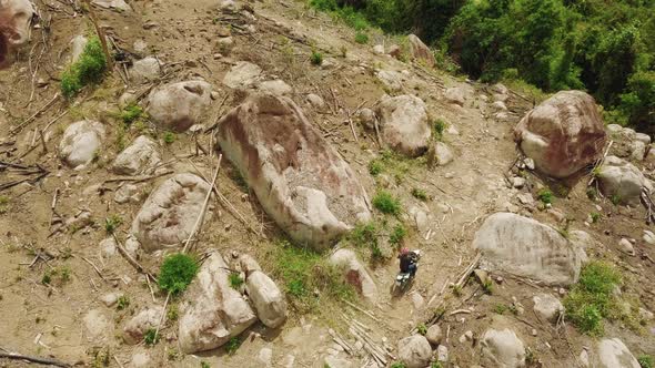 Aerial. Extreme Ride of a Dirt Biker on the Dangerous Hillside with Big Rocks.