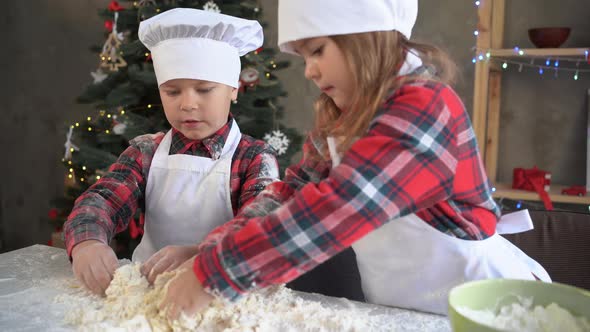 Two Children Cooks Kneading Dough on the Table