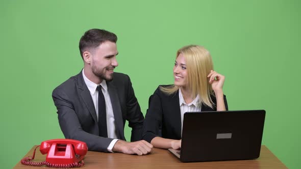 Young Businessman Flirting with Young Businesswoman and Getting Angry on Telephone