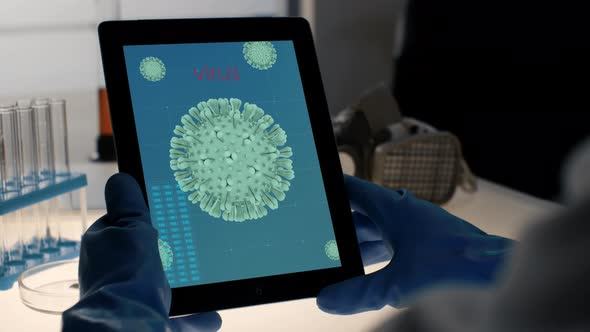 Coronavirus Image on Tablet PC Display in Hands in Protective Gloves in Modern Laboratory. Scientist