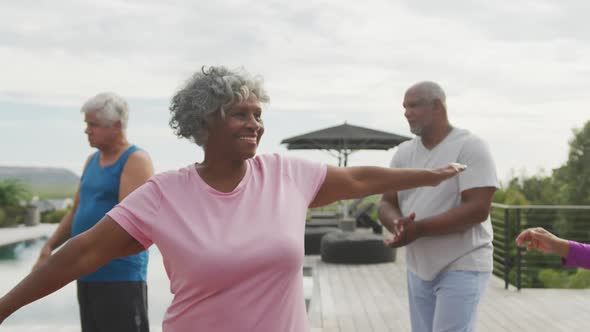 Happy senior diverse people practicing yoga in garden at retirement home