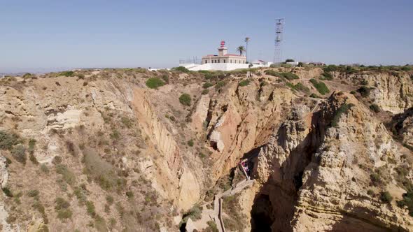 Low angle view of Ponta da Piedade lighthouse, Algarve, Aerial pullback revealing headland and cliff