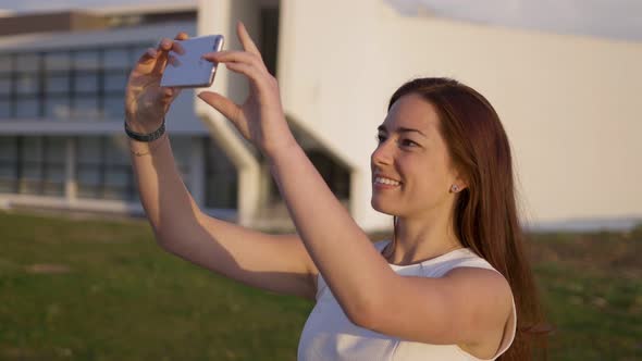 Beautiful Young Woman with Long Hair Taking Selfie During Sunset