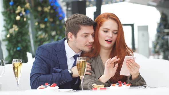 Adorable Young Couple Views Negative Video on a Smartphone Screen