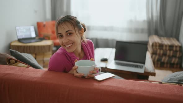 Cheerful Girl Sits at Home on the Couch with a Big Cup of Tea