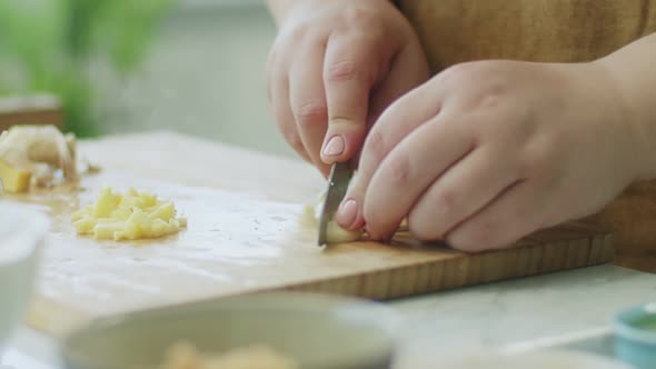 Woman cutting garlic on wooden board in kitchen