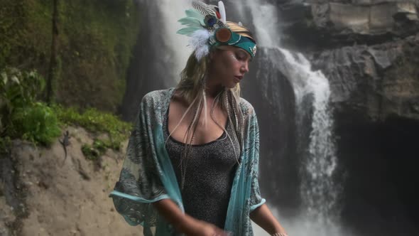 Concentrated Young Woman in Ethnic Colored Attire Meditates Close to Falling Stream