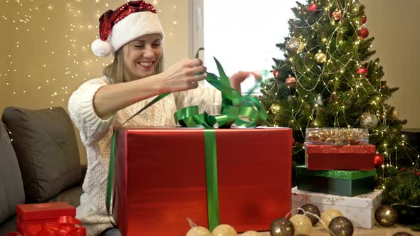 Charming Woman in Santa Hat Lovingly Wraps Gifts for Loved Ones