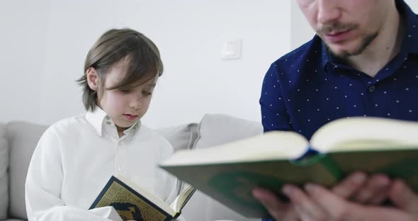 Muslim Father and Son Reading From the Quran During Ramadan