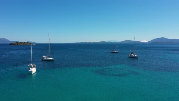 Sailboats, yachts and catamarans anchored on the shores with beach of the islands with vegetation in