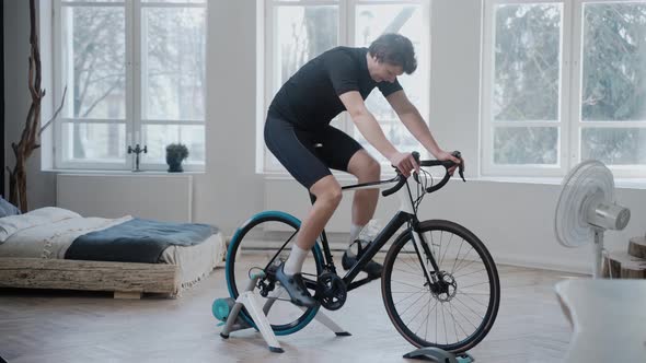 Side View of a Cyclist Training on an Exercise Bike Staying at Home