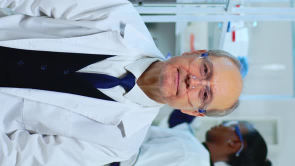 Vertical Video Senior Biochemist Sitting in Lab Looking Satisfied at Camera