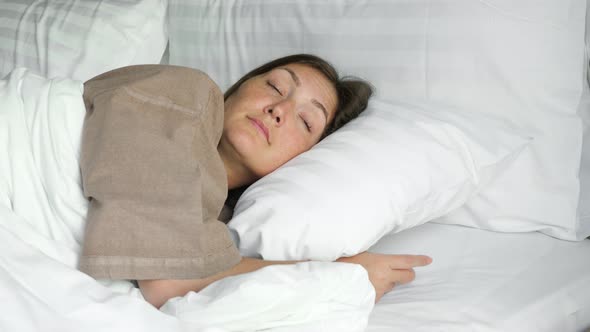 Happy Woman Sleeps in Bed with Blanket and Pillows in Hotel