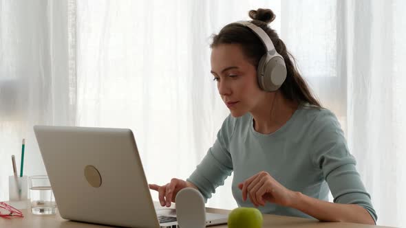 Young Woman with Headphones Working on Laptop at Home
