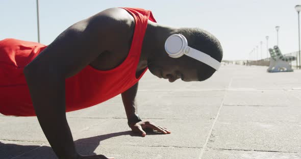 Focused african american man doing press ups, exercising outdoors by the seaside