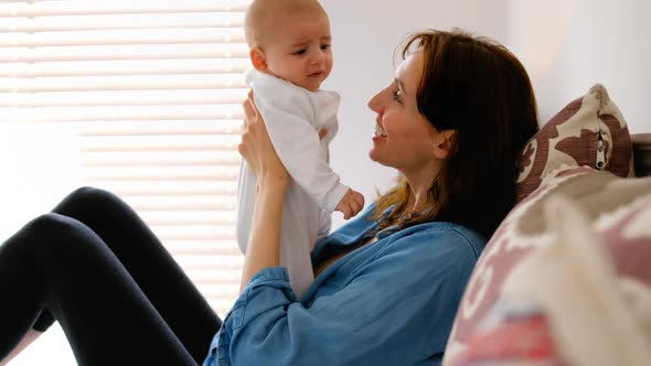 Young mother sitting on bed kissing her crying baby in the bedroom 4k