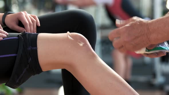 Therapist Applying Ointment Cream on Female Knee.