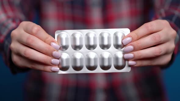 Woman Presenting a Hand of Foil-wrapped Pills