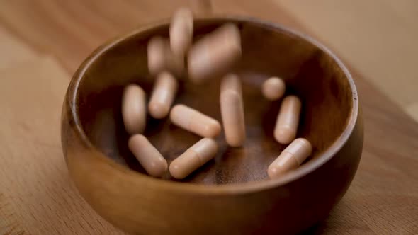 Vitamin B capsules falling in slow motion in a wooden bowl