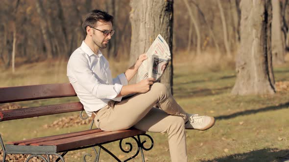 Businessman Relaxing And Reading Fresh Newspaper.Man Sitting On Bench And Reading Newspaper.