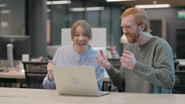 Young Man and Woman Celebrating Success on Laptop