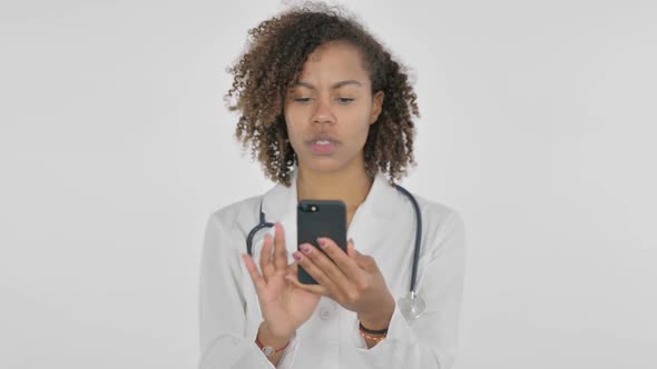 African Female Doctor Browsing Smartphone on White Background