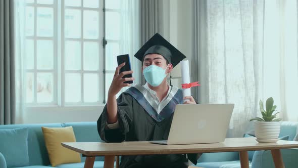 Excited Asian Man Wearing Protection Face Mask During An Online Video Call By Mobile Phone alt