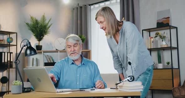 Elderly Bearded Man Showing Something to His wife on Laptop